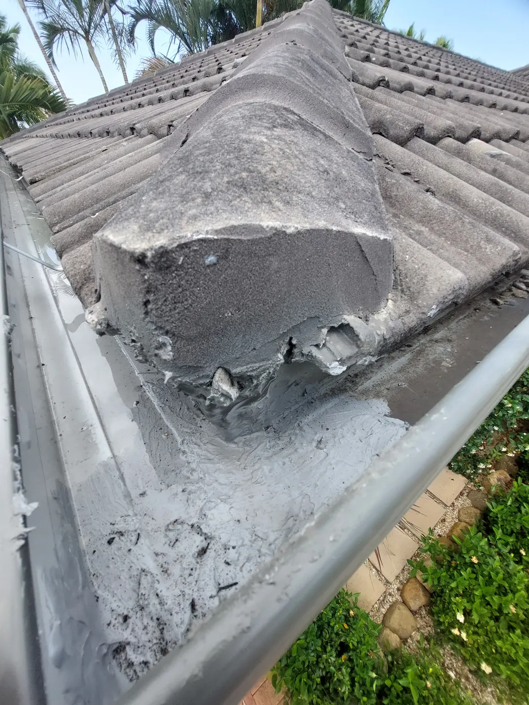 Ageing tiled roof ridge capping and gutter due for repair on a Gold Coast home
